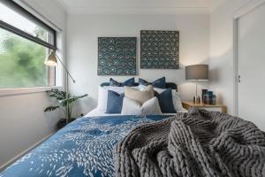 um quarto com uma cama azul e uma janela em VAQUAY Contempo In Flemington em Melbourne