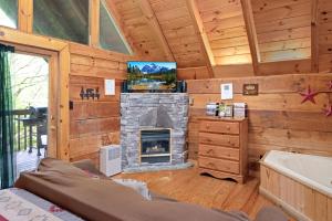 a living room with a fireplace and a tv at Cozy Cabin! Hot Tub, King Bed, Fireplace, & Pool in Gatlinburg