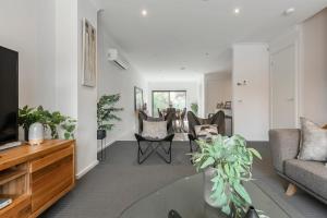 uma sala de estar com um sofá e uma televisão em VAQUAY Contempo In Flemington em Melbourne