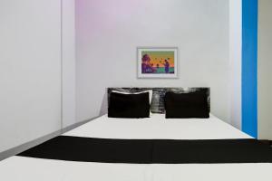 Bett in einem weißen Zimmer mit zwei schwarzen Kissen in der Unterkunft OYO Flagship Hotel RK Palace in Pukhrāyān