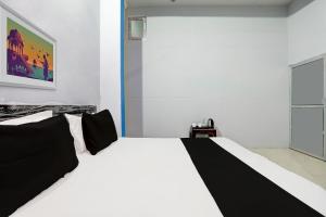 ein weißes Bett mit schwarzen Kissen in einem Zimmer in der Unterkunft OYO Flagship Hotel RK Palace in Pukhrāyān