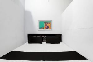Dieses weiße Zimmer verfügt über ein Bett mit schwarzen Kissen. in der Unterkunft OYO Flagship Hotel RK Palace in Pukhrāyān