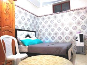 um pequeno quarto com uma cama e uma cadeira em Aziz House 2 em Tan-Tan