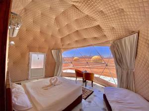 een slaapkamer met 2 bedden en een groot raam bij Katrina Rum camp in Wadi Rum