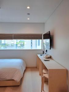 um quarto com uma cama, uma secretária e uma janela em Gloryinn em Seul