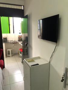 um quarto com um frigorífico e uma televisão na parede em La Playa Hospedagem em João Pessoa