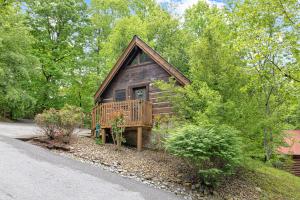 a log cabin with a porch and a deck at Cozy Cabin! Hot Tub, King Bed, Fireplace, & Pool in Gatlinburg
