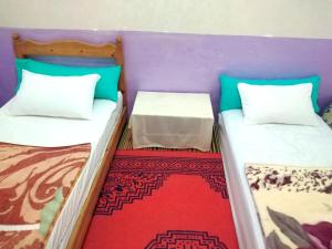2 Einzelbetten in einem Zimmer mit einem roten Teppich in der Unterkunft Aziz House 1 in Tan-Tan