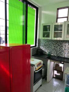 a kitchen with a red refrigerator and a green screen at La Playa Hospedagem in João Pessoa