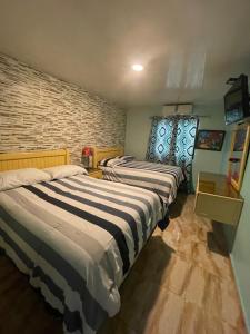 a bedroom with three beds and a brick wall at Hotel La Romana Center in La Romana
