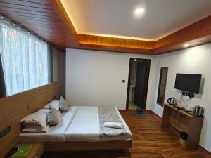 a bedroom with a bed and a flat screen tv at Hotel Namgyal House in Gangtok