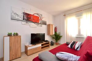 un soggiorno con divano rosso e TV di Playa - Garaje - Moderno - Arena23 a Gijón