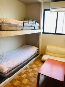 Kleines Zimmer mit 2 Etagenbetten und einem Tisch in der Unterkunft Relak Guest House 登別 Station in Noboribetsu