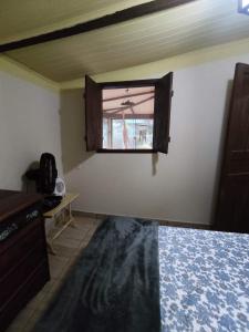ein Schlafzimmer mit einem Fenster und einem Bett in einem Zimmer in der Unterkunft Chácara Toca da Zuca in Divino de São Lourenço