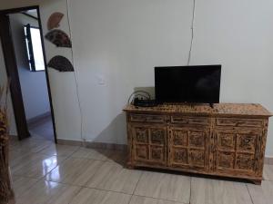 - une commode en bois avec une télévision en haut dans l'établissement Chácara Toca da Zuca, à Divino de São Lourenço