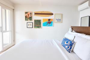 Dormitorio blanco con cama y cuadros en la pared en Laguna Surf Lodge by SCP Hotels en Laguna Beach