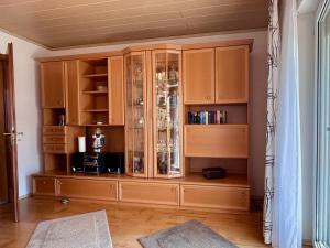 un gran armario de madera con puertas de cristal en una habitación en Ferienwohnung Uschis Sommergarten - Gartenidyll im Allgäu, en Wangen im Allgäu