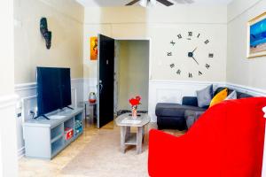 Red Hassell Manor في بورت أنطونيو: غرفة معيشة مع أريكة وساعة على الحائط