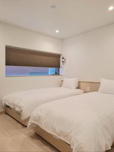 2 camas en un dormitorio con ventana en Gloryinn, en Seúl