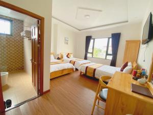 Cette chambre comprend deux lits et une télévision. dans l'établissement HANZ Hoa Dang Hotel, à Đà Lạt