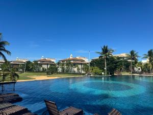 a large swimming pool with chairs and palm trees at Golf Ville Resort in Aquiraz