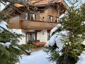 a wooden house with a bench in the snow at Haus 76 Top 1 in Krimml