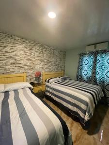 2 camas en una habitación con una pared de ladrillo en Hotel La Romana Center, en La Romana