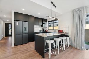 una cocina con armarios negros y taburetes de bar en Break on Bragato - Cromwell Holiday Home, en Cromwell