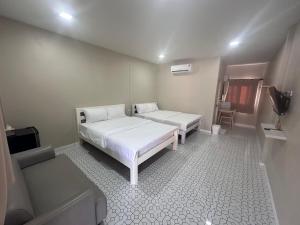 a small room with two beds and a tv at Juni House Chumphon in Chumphon