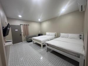 a room with two beds and a chair in it at Juni House Chumphon in Chumphon