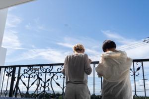 Jacuzzi Terrace Okinawa IMS في موتوبو: شخصين واقفين على شرفة تطل على السماء