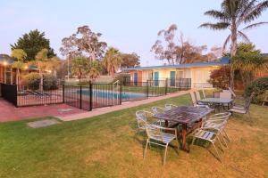 a patio with a table and chairs and a pool at Ocean Views Motel Lakes Entrance in Lakes Entrance