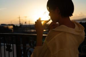 Jacuzzi Terrace Okinawa IMS في موتوبو: a young woman drinking a glass of wine at sunset