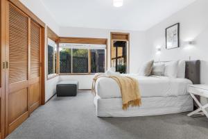 a bedroom with a white bed and a desk at Tree Top Retreat in Central City - By KOSH BNB in Hamilton