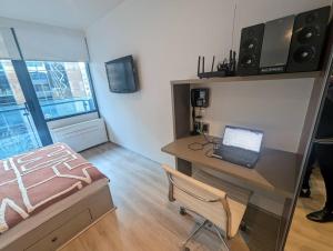 a room with a desk with a laptop and a bed at Cosy City Studio Apartment in Melbourne