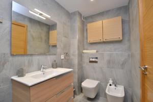 ヒホンにあるPlaya - Garaje - Moderno - Arena23のバスルーム(洗面台、トイレ、鏡付)