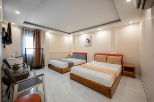 una habitación de hotel con 2 camas y una silla en Joy Inn Cong Hoa Hotel en Ho Chi Minh