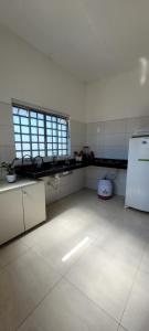 Espaço inteiro - Apto de 1 quarto في بوم جيسوس دي لابا: مطبخ كبير مع أرضية بيضاء ونافذة