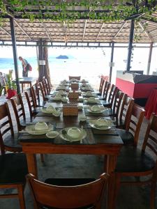 einen langen Holztisch mit Stühlen und Tellern darauf in der Unterkunft SCARLET SAILS BUNGALOW in Koh Rong