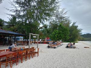 een groep mensen die aan tafels op het strand zitten bij SCARLET SAILS BUNGALOW in Koh Rong Island