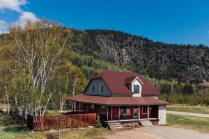 a house with a red roof and a mountain at Le Chalet des Coteaux in LʼAnse-Saint-Jean