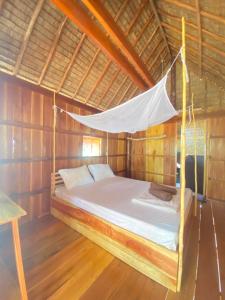 uma cama num quarto de madeira com uma rede mosquiteira em Lily's Beach Bungalows em Koh Rong Island