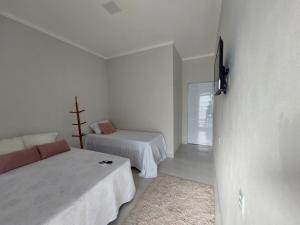biały pokój z 2 łóżkami i telewizorem w obiekcie Pousada Luz do Sol w mieście Piranhas