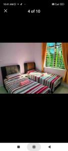 two beds sitting next to a window in a room at E Am Kelulut Homestay in Marang +4 photos