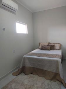 Bett in einem weißen Zimmer mit Fenster in der Unterkunft Pousada Luz do Sol in Piranhas