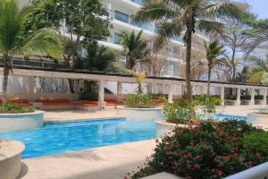 a hotel pool with palm trees and a building at Morros 3 Frente al Mar - Piscinas y Jacuzzi in Cartagena de Indias +55 photos