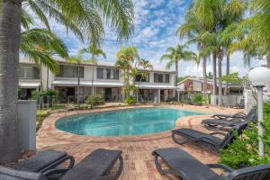 a swimming pool with lounge chairs and palm trees at 10 Noosa Sound in Noosa Heads