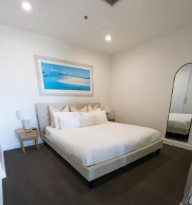 a white bedroom with a large bed with white pillows at Glenelg Oasis, Pool, Gym, Spa & Sauna, Free Parking, City Views in Glenelg