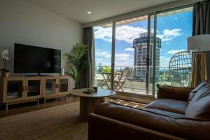 a living room with a couch and a large window at Glenelg Oasis, Pool, Gym, Spa & Sauna, Free Parking, City Views in Glenelg