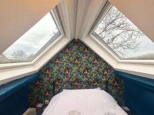 a bed in a room with two windows at Retraite Romantique en Brenne: Piscine, Confort et Nature - FR-1-591-587 in Chitray